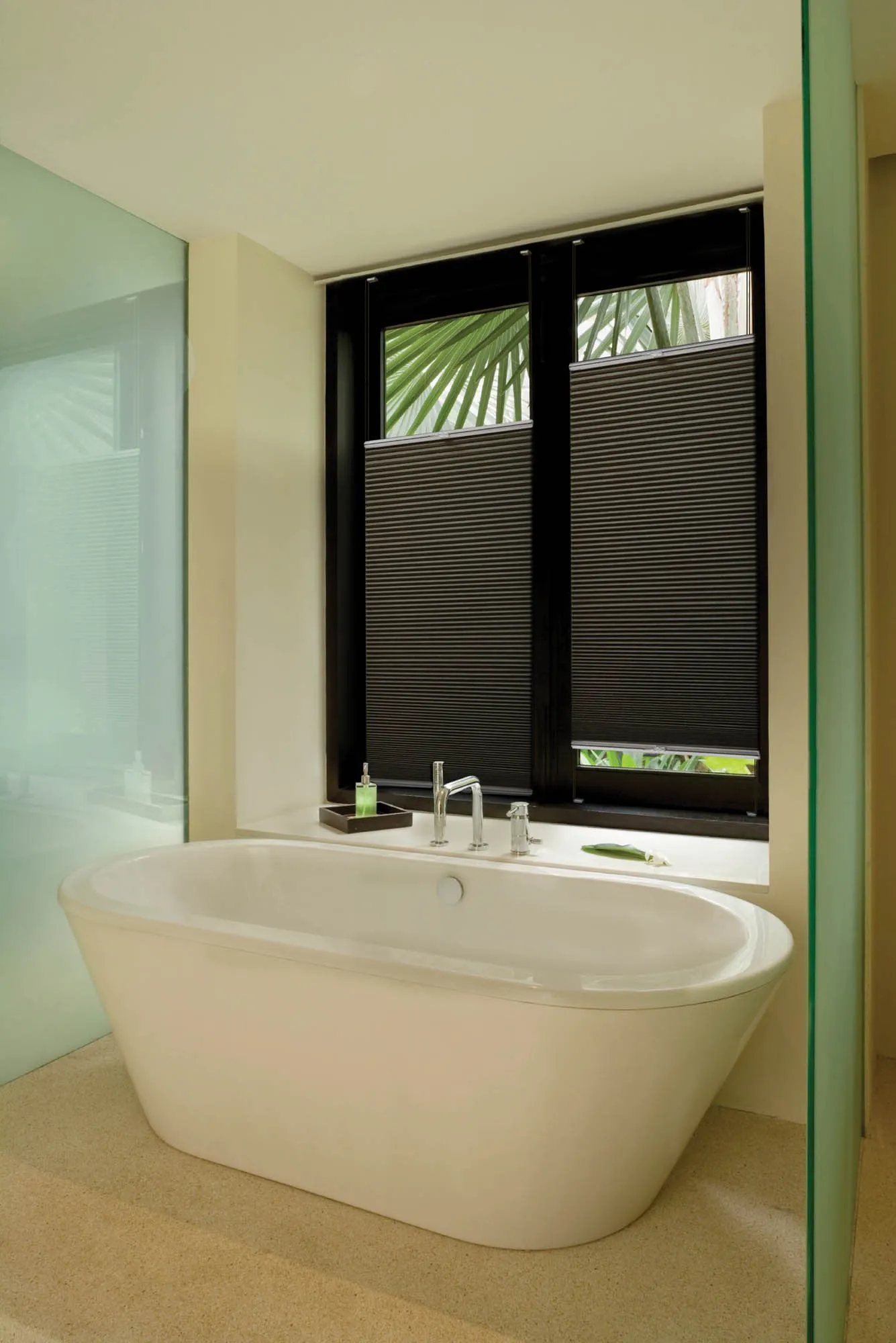 Charcoal honeycomb blinds on a window behind a freestanding bath