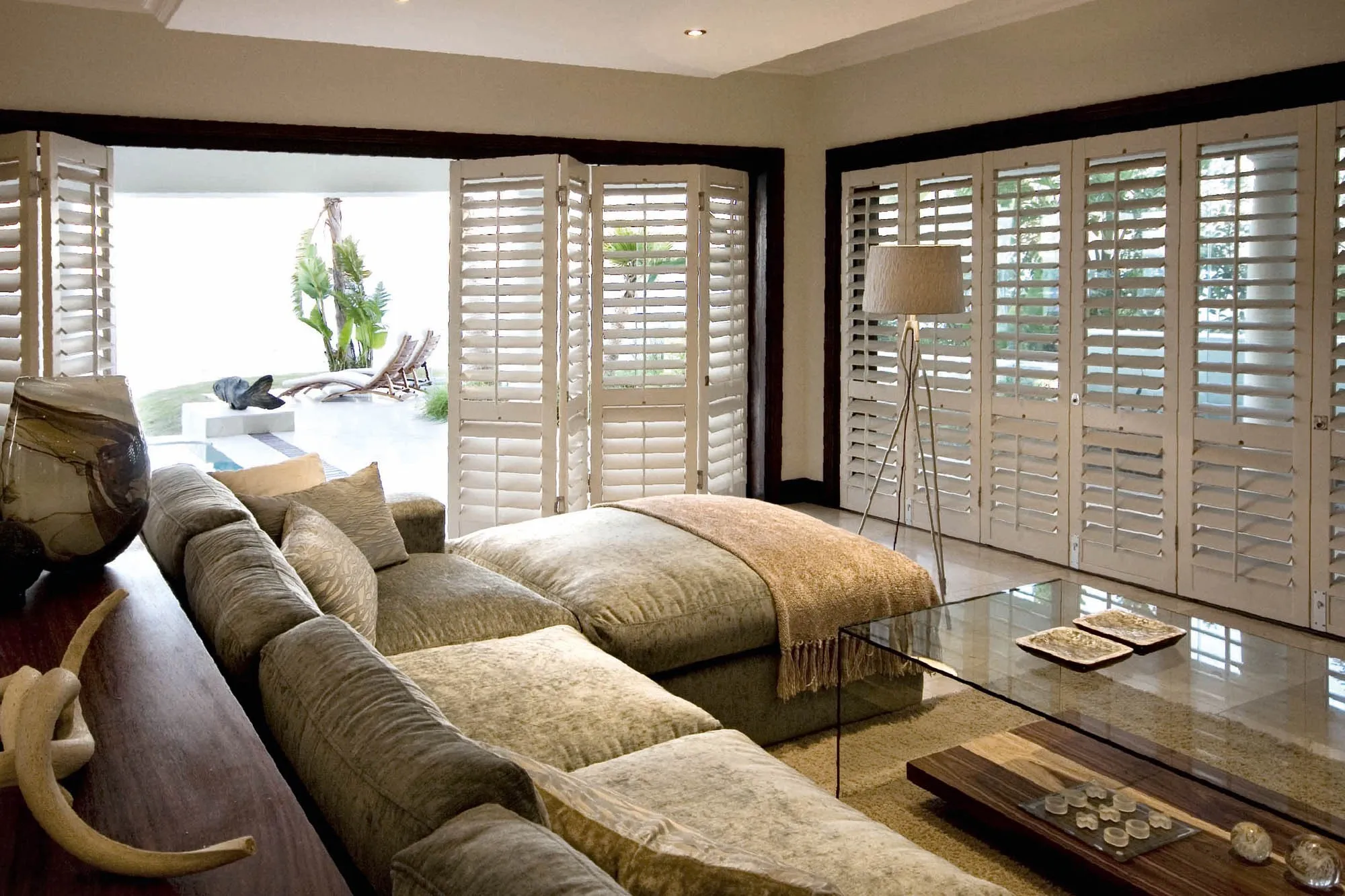 Living room with white plantation shutters across a wall of windows